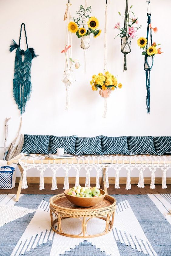 a modern macrame daybed with tassels, blue printed pillows and colorful macrame hangings for planters